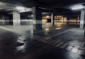 Sub-grade underground parking garage concrete slab and retaining walls treated with negative-side waterproofing barrier