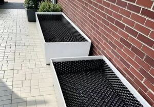 Vegetated green roof parapet flashing and root-barrier membrane edge sealed with chemical-resistant sealant