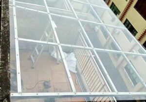 Clear flexible sealant bridging polycarbonate skylight panels and aluminum roof frame joints