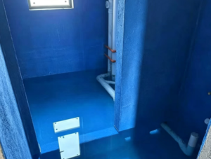 Full-coverage blue liquid waterproofing coating applied to floor slabs and lower wall substrates in a wet washroom enclosure