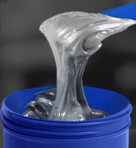 High-viscosity metallic gray LeakProof epoxy paste lifted with a spatula from a container for emergency leak repair and industrial cold welding
